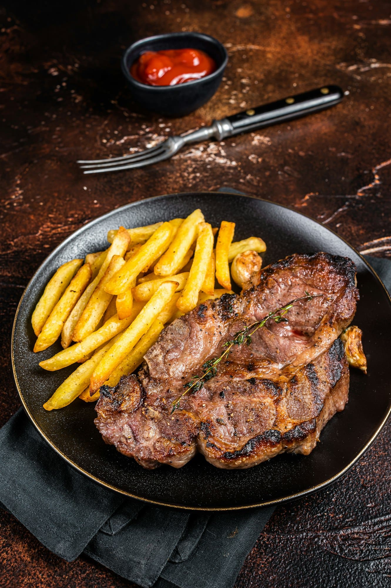 Roasted pork steaks from neck meat in plate with potato chips. Dark background. Top view