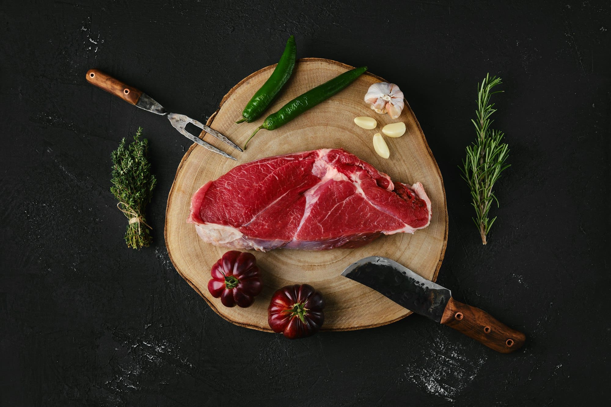 Top view of raw top sirloin beef steak on dark background